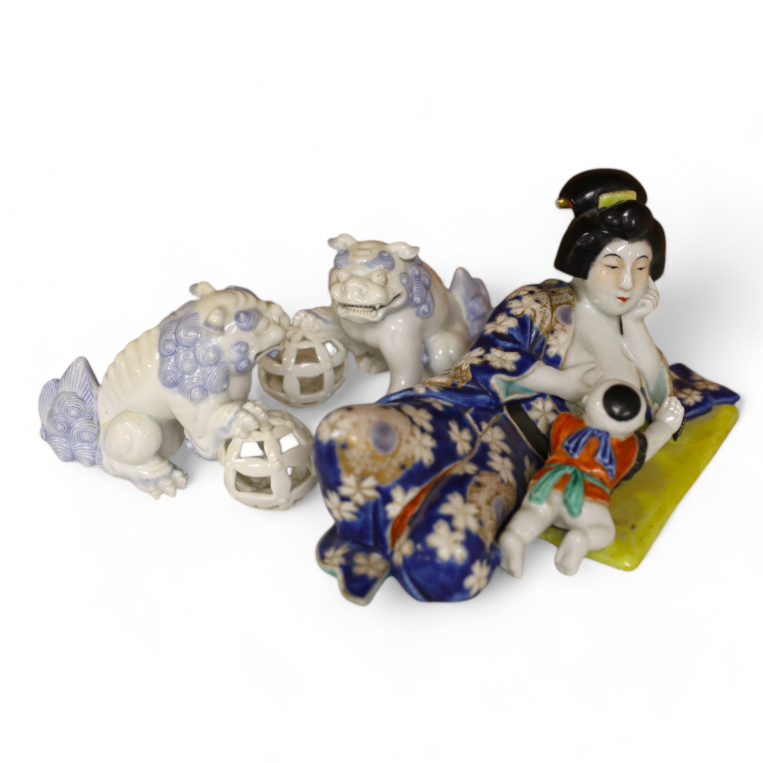 A Japanese enamelled reclining figure of mother and baby and two Hirado style shi-shi figures, reclining figure group 21cm wide. Condition - good